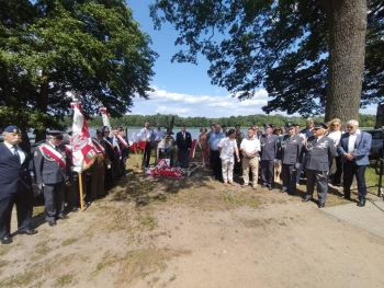 Na zdjęciu znajdują się piloci i osoby składające kwiaty przy pomniku